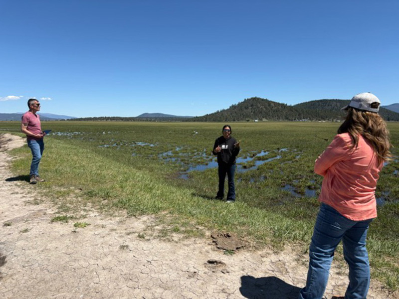 3 people surveying a watershed area
