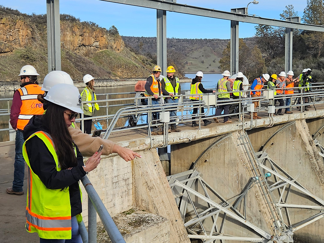 People standing on top of a dam wearing yellow safety vests and hard hats